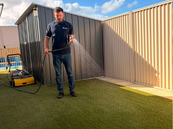 Baldivis Window Cleaning operator applying the final rinse-down stage to artificial turf